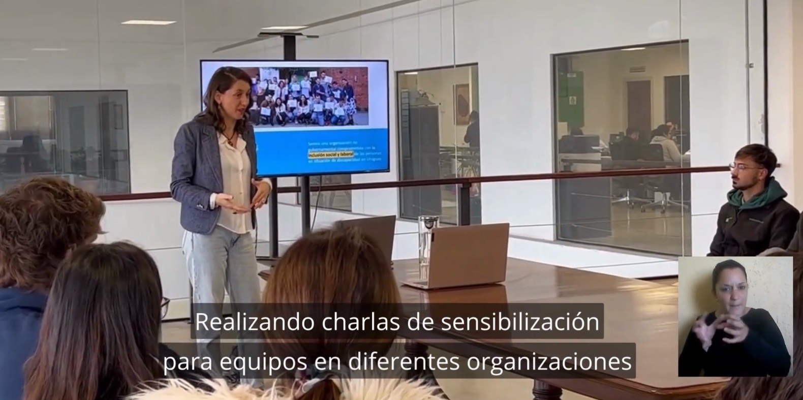 Captura de video que muestra a una mujer dictando a una charla en una sala de reuniones